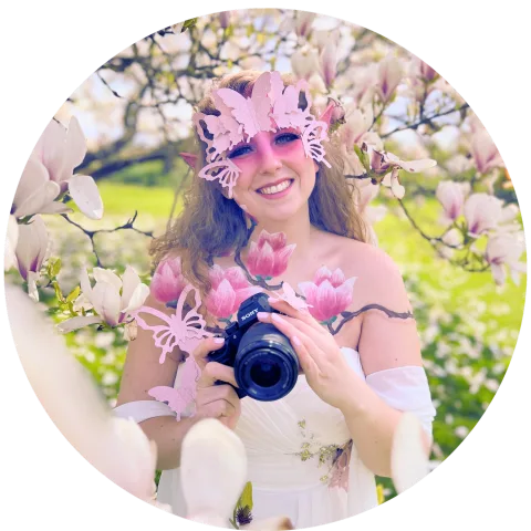 Anna Lena Dohmann mit Kamera und Blütenschmuck vor einem Magnolienbaum